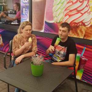 na zdjęciu widać dwie osoby siedzące przy stoliku w cukierni jedzące lody